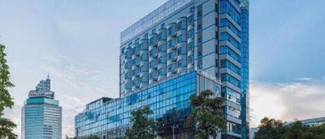 Een modern hotel met een glazen gevel, meerdere verdiepingen en een opvallende hoekligging.