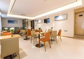 A modern hotel lobby with a reception desk, seating area, and a large window.