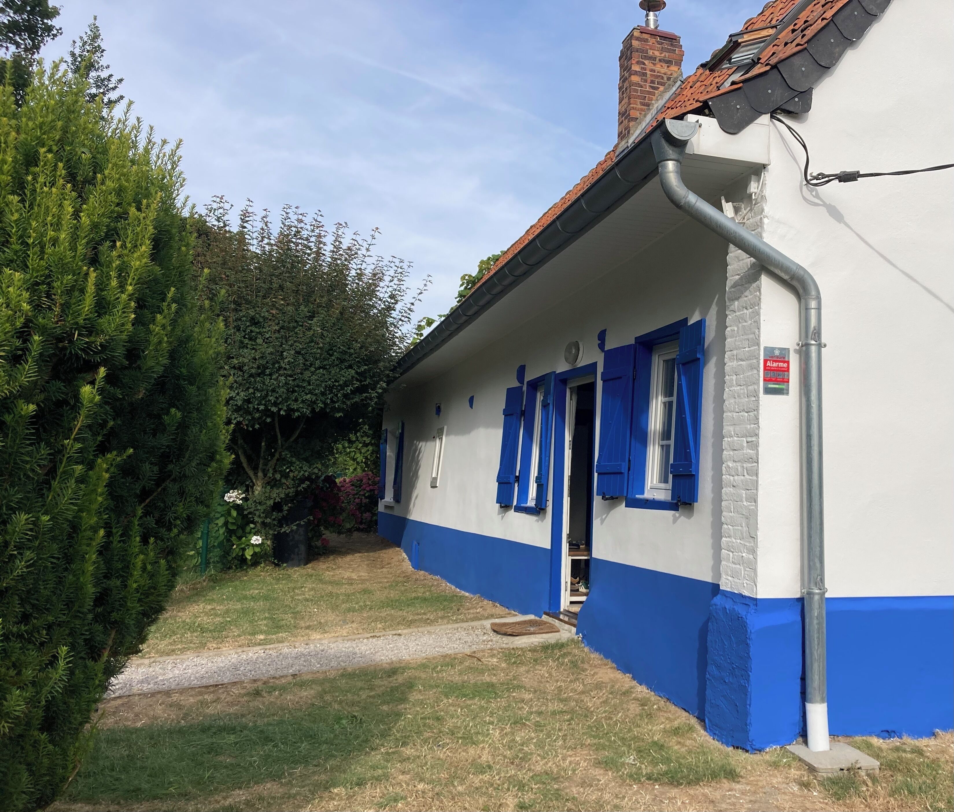 Een gebouw met een blauw-witte gevel, een duidelijke deur en een schoorsteen.