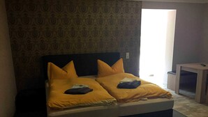 Una cama doble con dos almohadas, una mesita de noche y un papel tapiz estampado.