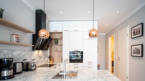 Una cucina moderna con un piano di lavoro in marmo, elettrodomestici in acciaio inossidabile e lampade a sospensione in rame.