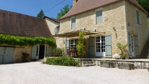 A stone building with a red-tiled roof, a covered porch, and a gravel driveway. - Beautiful, spacious & fully renovated house in the Dordogne (Saint-Cybranet)
