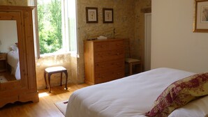 A bedroom with a bed, dresser, and a small stool. There is a window with a view of trees outside. - Beautiful, spacious & fully renovated house in the Dordogne (Saint-Cybranet)