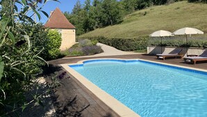 A rectangular swimming pool with a wooden deck and lounge chairs with umbrellas. - Beautiful, spacious & fully renovated house in the Dordogne (Saint-Cybranet)