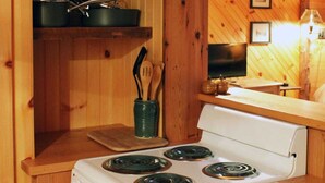 A wooden kitchen with a white stove, shelves with pots, and a wooden countertop. - Adirondack Riverfront Retreat (Jay)