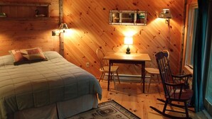 A cozy room with a bed, a table, and two chairs. - Adirondack Riverfront Retreat (Jay)