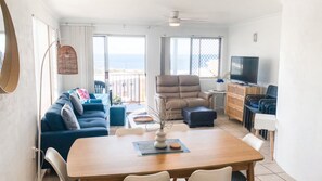 A modern living room with a sofa, a dining table, and a TV.