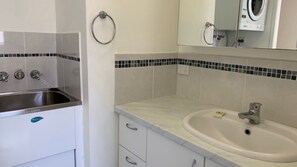 A bathroom with a sink, mirror, and a towel ring.