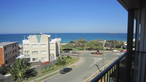 A coastal cityscape with buildings, a road, and a view of the ocean.