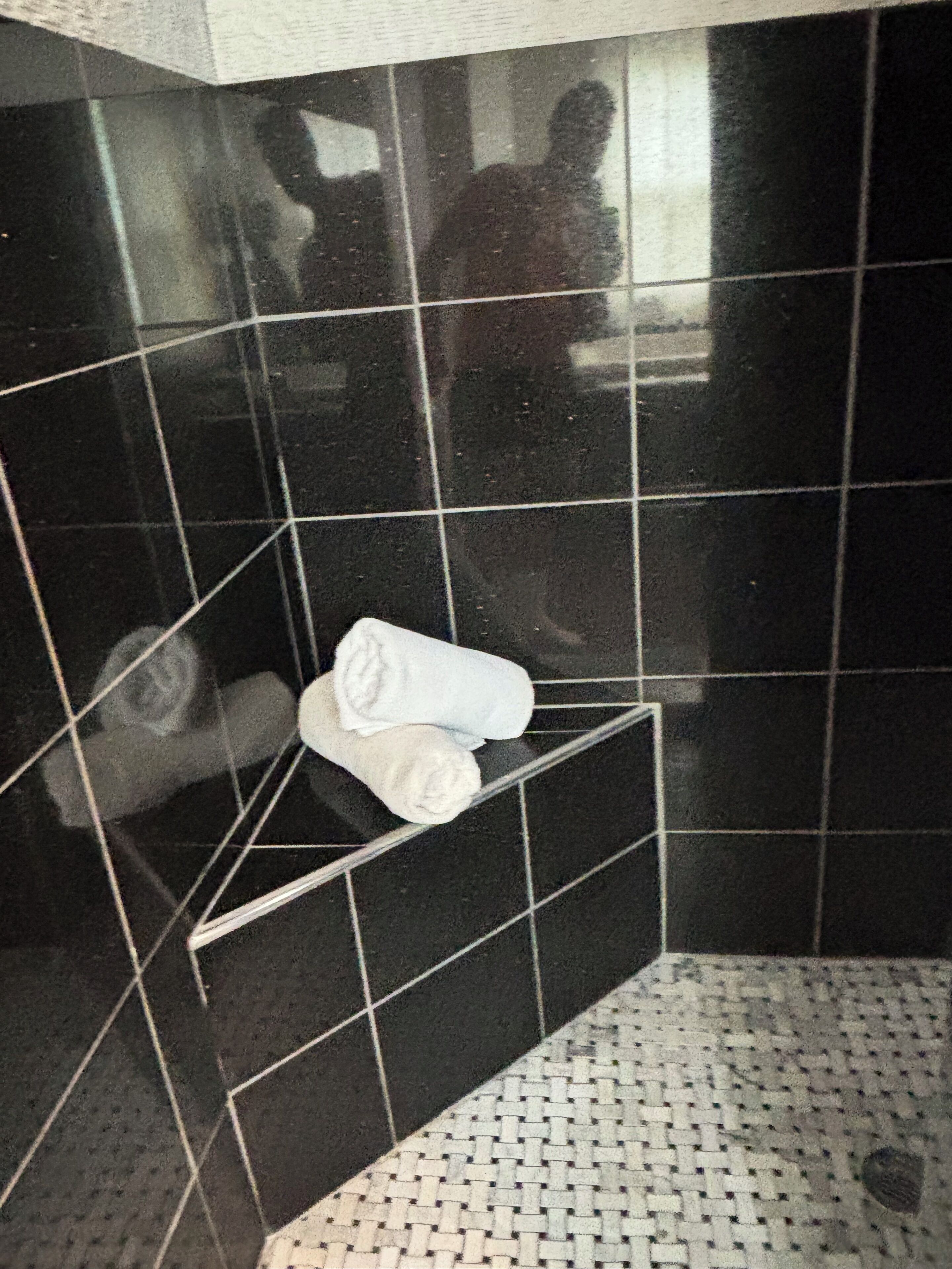 Un baño con piso de baldosas, toallero y zona de ducha.
