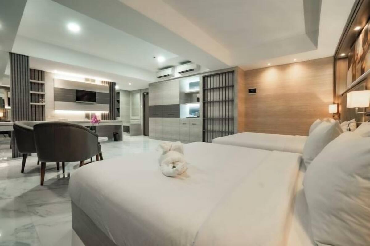 A modern hotel room with a large bed, a desk, and a seating area.