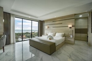 Quarto moderno com uma cama grande, mesa de cabeceira, uma cadeira e vista para a cidade.