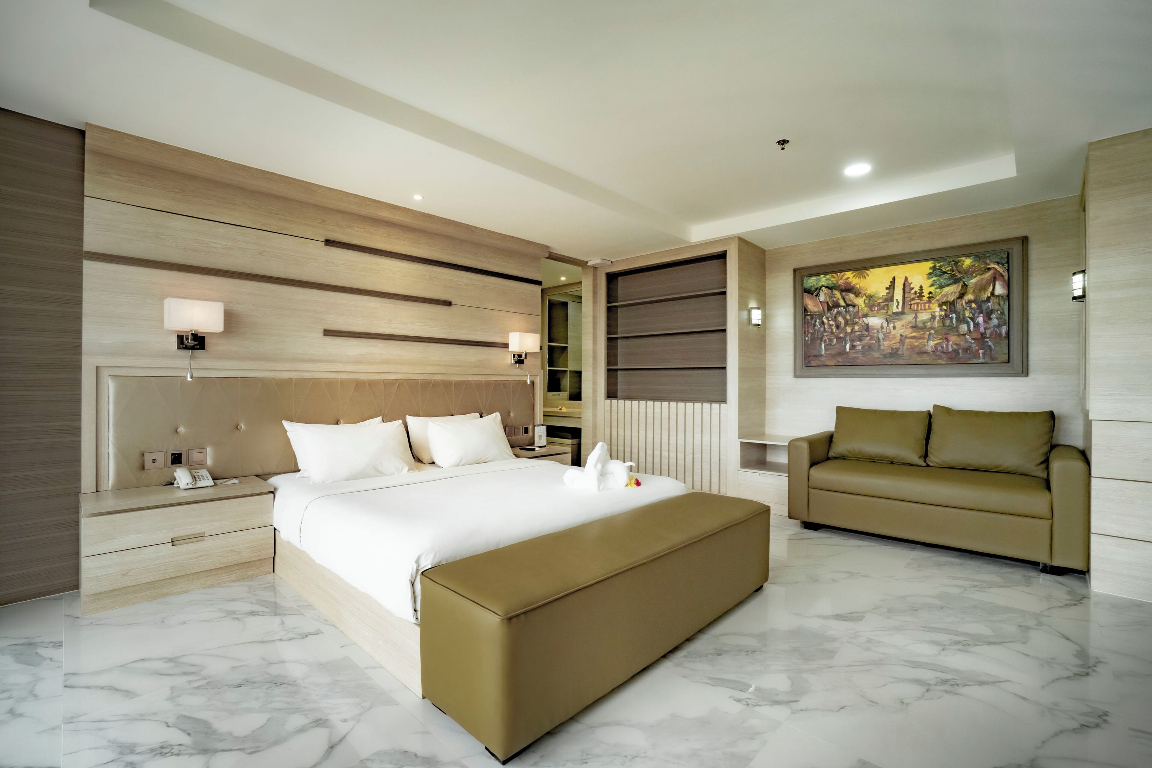 Une chambre d’hôtel moderne avec un grand lit, un canapé, un sol en marbre, un tableau au mur et une tête de lit en bois.