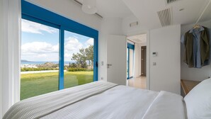Ein Schlafzimmer mit einem großen Bett, Blick ins Freie und einer Tür zu einem weiteren Raum.