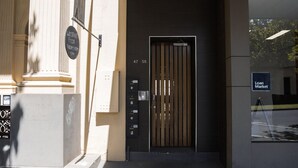 A building entrance with a wooden door, a sign for 'Woodcraf Pizza Fridays from 5 PM', and a 'Loan Market' sign. - Spacious, modern apartment right in the Bendigo CBD (Bendigo)