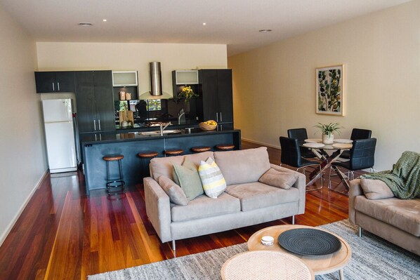 A modern living room with a grey sofa, a coffee table, and a dining area with a small table and chairs.