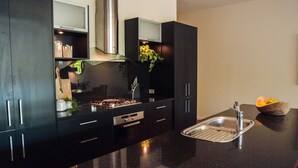 A modern kitchen with dark cabinetry, a stainless steel sink, and a built-in stove. - Spacious, modern apartment right in the Bendigo CBD (Bendigo)