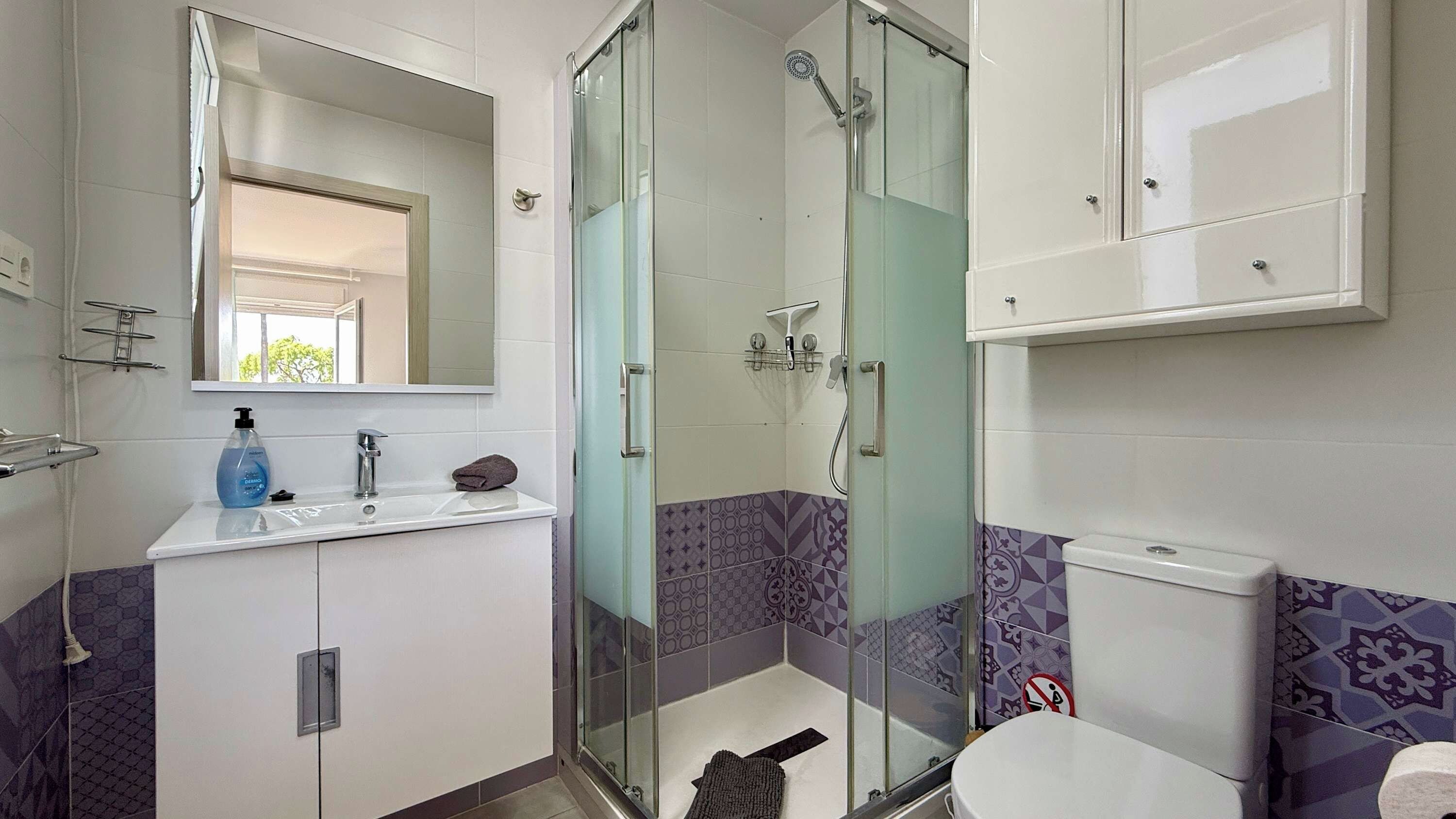Une salle de bain moderne avec une douche à parois de verre, un lavabo blanc et des toilettes.