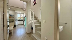 Ein Flur, der zu einer Küche mit Treppe, Essbereich und Außenblick führt.