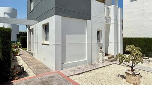 A modern two-story house with a flat roof, a balcony, and a small garden area with potted plants. - T-0721, Havanna, villa in Mimosa II with 3 bedrooms (Els Poblets)