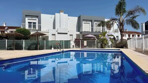 A swimming pool with a clear blue water surface, surrounded by a white fence, and a modern building with balconies in the background. - T-0721, Havanna, villa in Mimosa II with 3 bedrooms (Els Poblets)