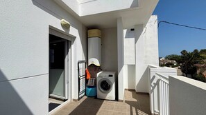A balcony with a washing machine, a water heater, and a door leading to an interior space. - T-0721, Havanna, villa in Mimosa II with 3 bedrooms (Els Poblets)