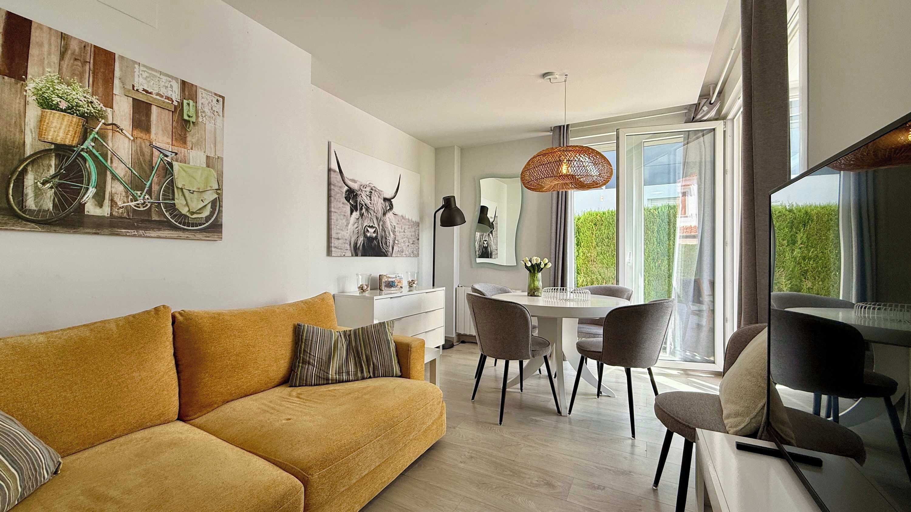 A modern living room with a sofa, dining table, chairs, and artwork on the walls.