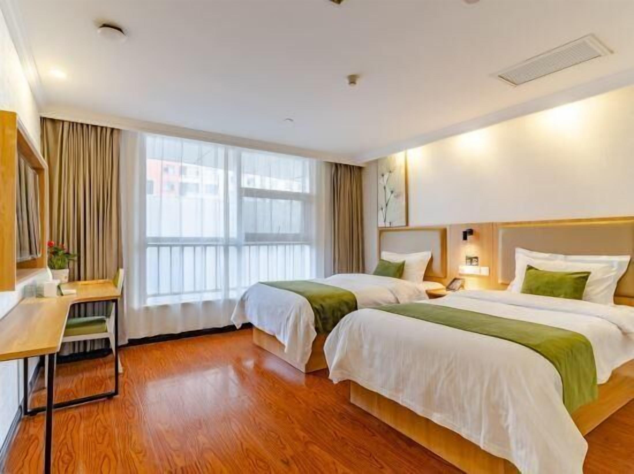 Een hotelkamer met twee bedden, een bureau en een groot raam.
