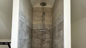 A modern shower room with tiled walls and a floor, a showerhead, and a hand shower. - Chambre Bonheur (Romeries)