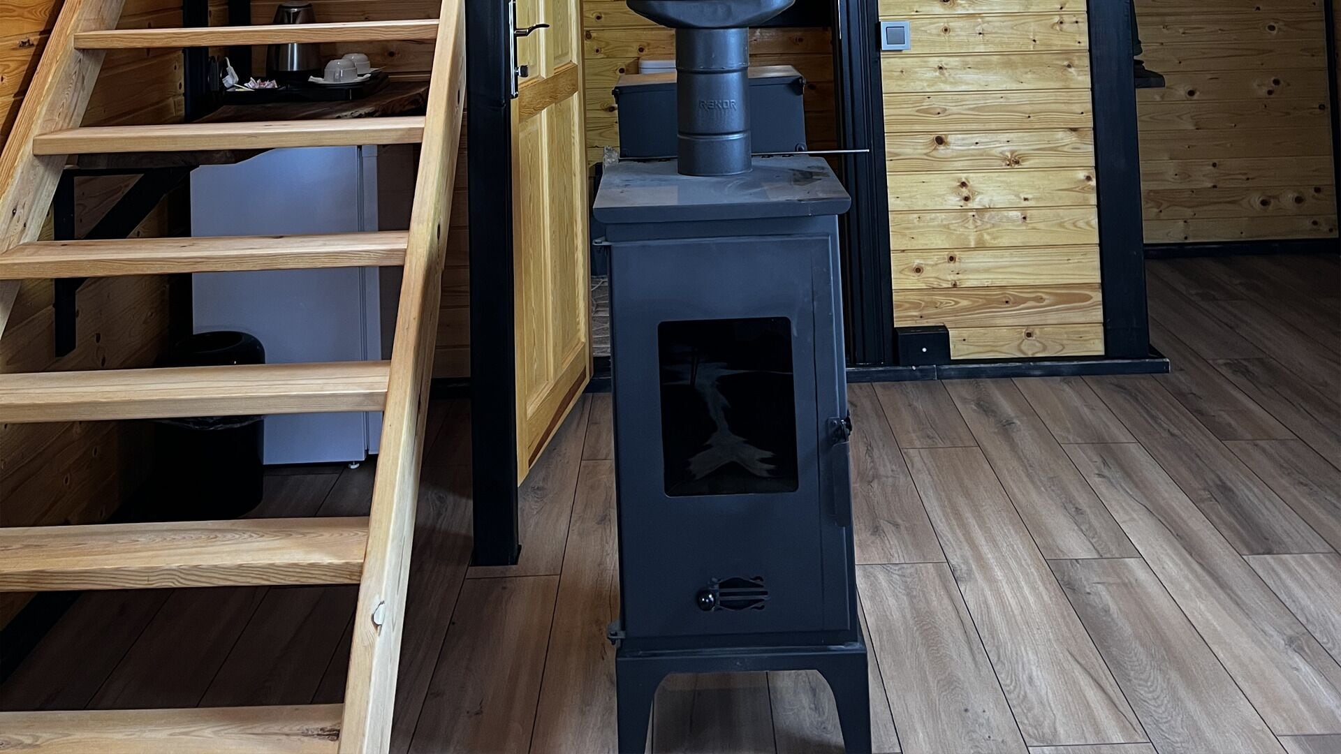 Una cocina moderna con estufa integrada, repisas de madera y una escalera.