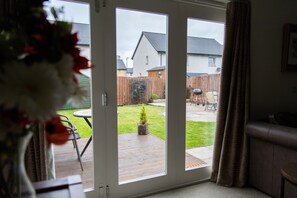 Enjoy the serene view of the backyard from the comfort of your room, featuring a deck, lawn, and outdoor furniture.