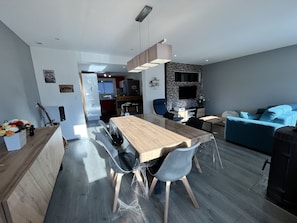 A modern living space with a dining area, a kitchen, and a seating area.