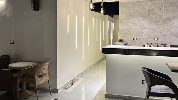Un área de cocina exterior moderna con barra, asientos e iluminación colgante.