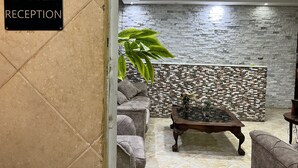 Un área de recepción con pared de piedra, asientos acolchados y una mesa de centro.