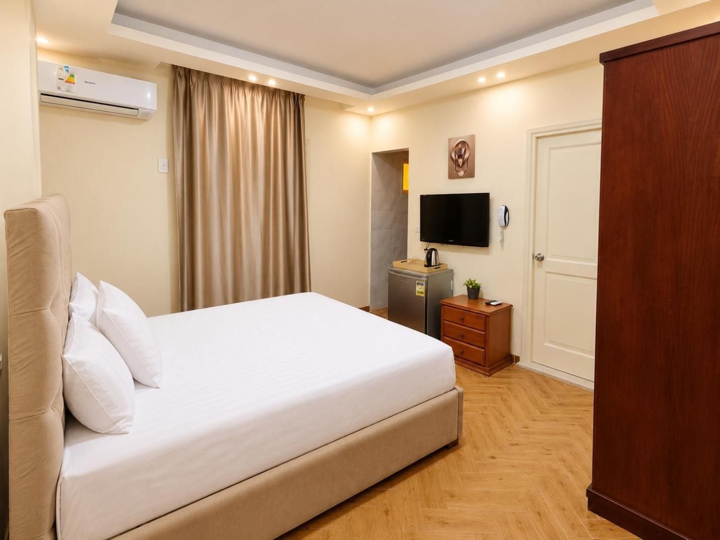 A hotel room with a bed, a desk, a television, and a wardrobe.
