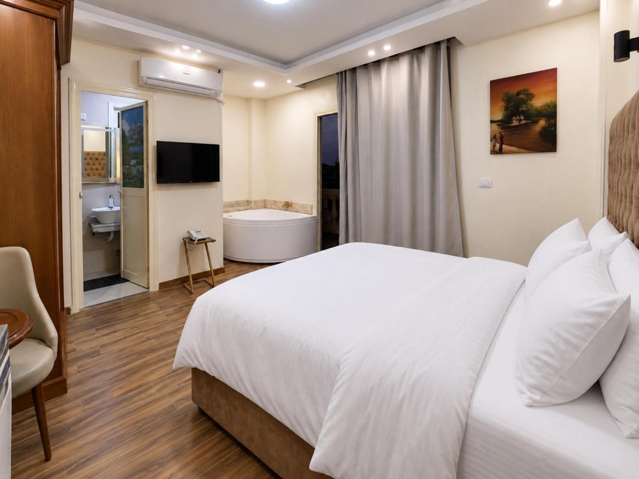 Habitación de hotel con cama, baño, televisor y un cuadro en la pared.