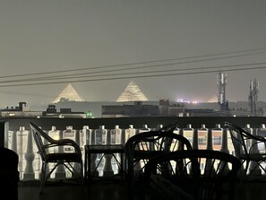 Ein Balkon mit Stühlen und Blick auf Pyramiden in der Ferne.