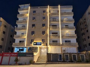 A multi-story hotel with balconies, a sign for 'Pyramids Gardens Hotel,' and a 'Greens lounge' sign.