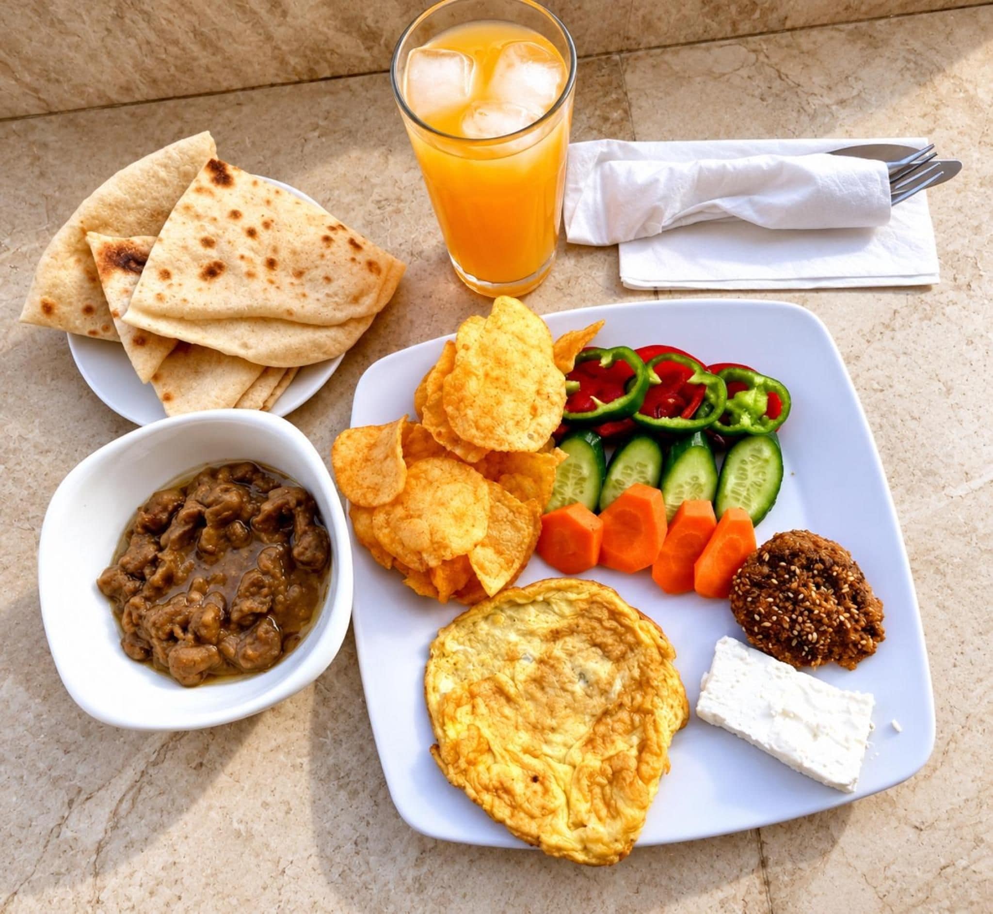 Un repas composé de pains plats, d’une salade, d’un bol de chutney et d’un verre de jus d’orange.
