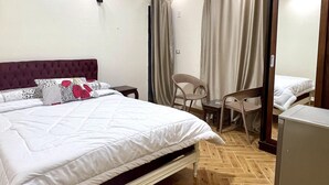 Un dormitorio con una cama, una silla, un escritorio y un espejo.