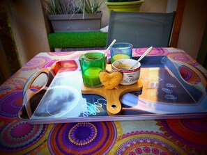 A tray with a heart-shaped cookie, a green glass, a mug with a spoon, and a colorful tablecloth.