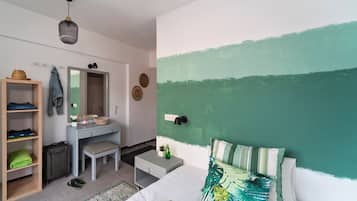 Un dormitorio con cama, escritorio, silla, una mesita, maleta y armario.
