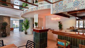 A reception area with a neon sign, a counter, and a seating area with a menu.