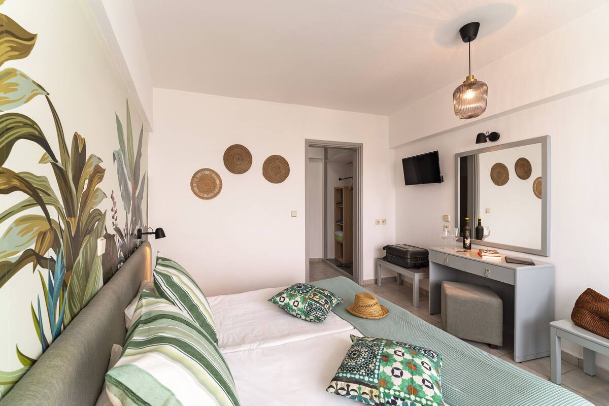 Ett modernt hotellrum med en säng, ett skrivbord, en spegel och en TV.