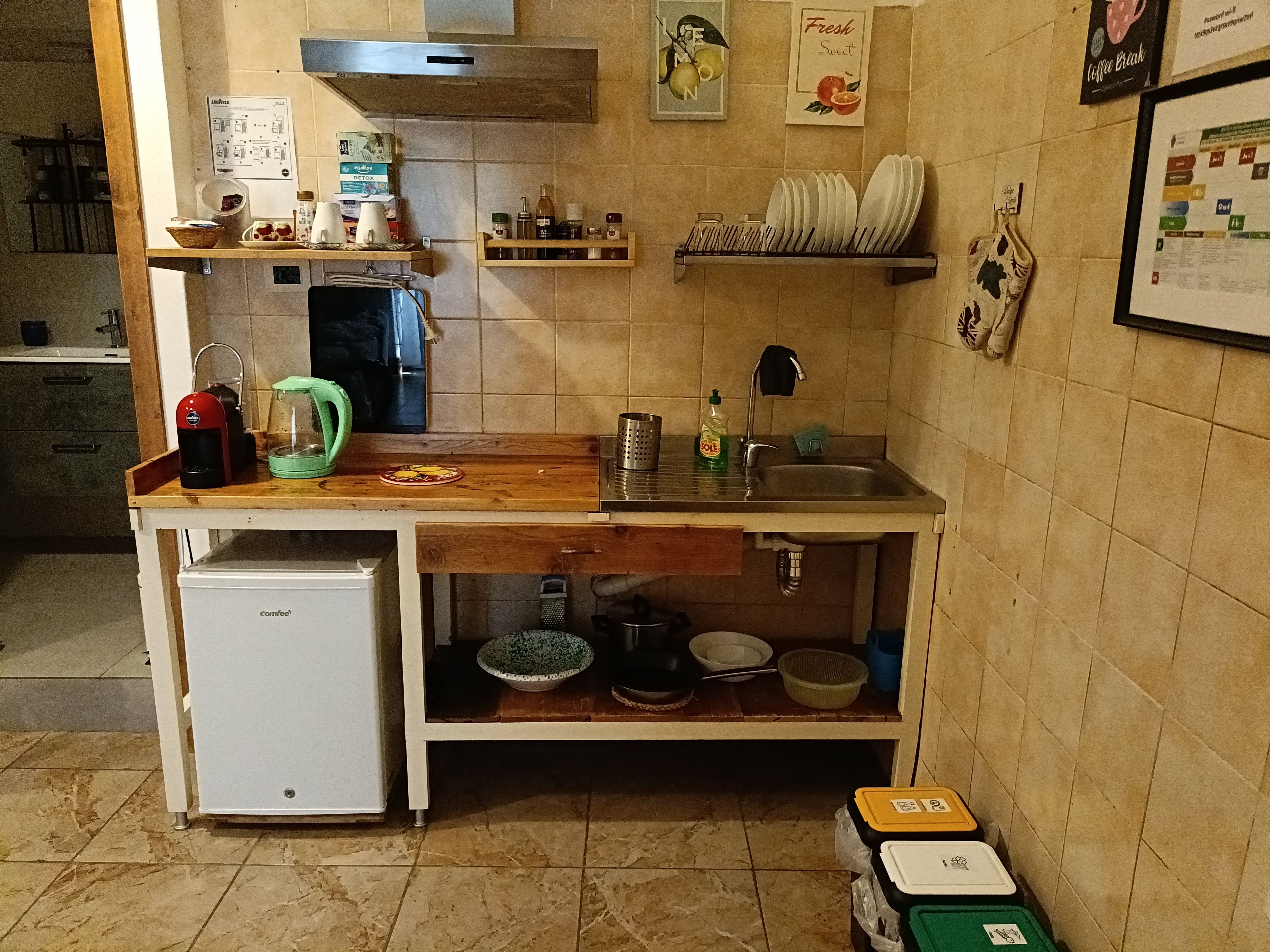 Eine kleine Küche mit Kaffeemaschine, kleinem Kühlschrank und Spüle.