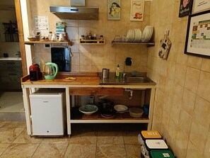 Cozinha compacta com cafeteira, mini geladeira e pia.