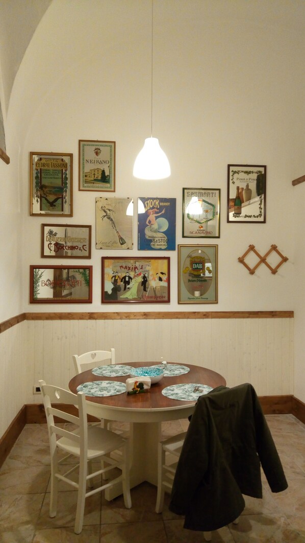 A dining area with a round table, white chairs, and a hanging light fixture.