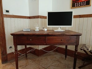 Ein Holztisch mit einem Computermonitor, Büchern und einem Glas.