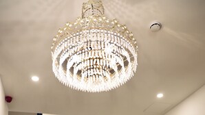 A grand chandelier, a staircase, and a reception area with a sign. - The Mike Hotel (Cospicua)