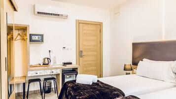 Une chambre d’hôtel comprenant un lit, un bureau avec une chaise, une armoire et un miroir.